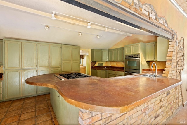kitchen with stainless steel appliances, a peninsula, a sink, vaulted ceiling, and green cabinets