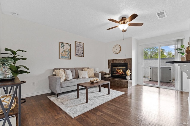 living area with ceiling fan, dark wood finished floors, baseboards, a high end fireplace, and visible vents