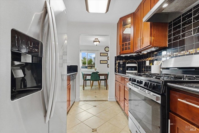 kitchen with backsplash, brown cabinets, under cabinet range hood, stainless steel appliances, and light tile patterned flooring