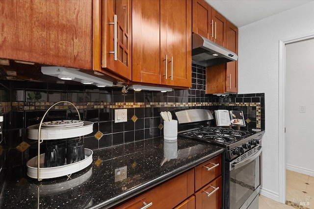 kitchen featuring brown cabinets, under cabinet range hood, stainless steel gas range oven, and tasteful backsplash