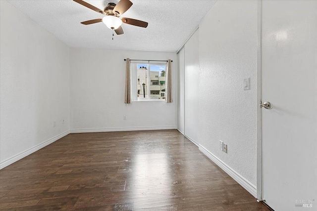 unfurnished room with a textured ceiling, ceiling fan, baseboards, and wood finished floors