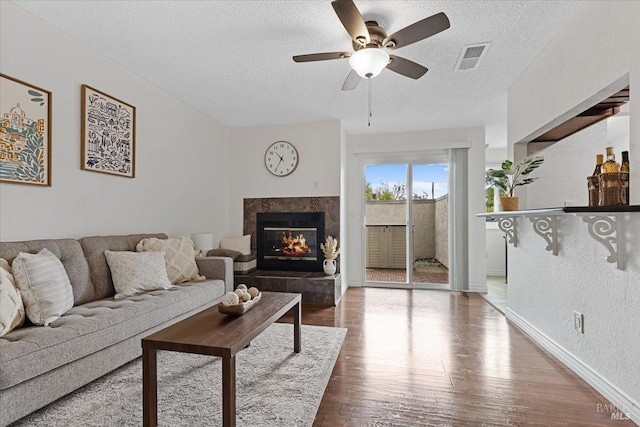 living room with a textured ceiling, ceiling fan, and wood finished floors