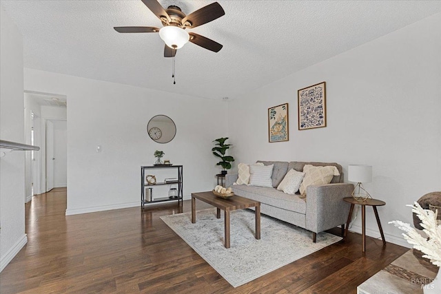 living room featuring a textured ceiling, baseboards, a ceiling fan, and wood finished floors