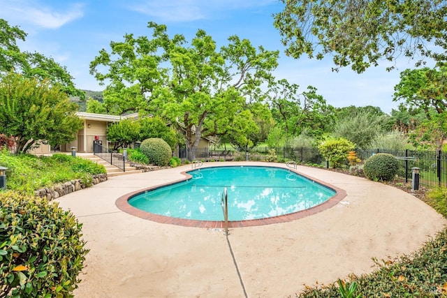 pool with a patio area and fence