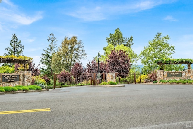 view of road with a gate and curbs