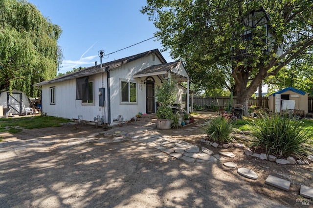 view of front of property featuring fence, a patio area, an outbuilding, and a storage shed
