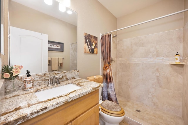 bathroom with toilet, vanity, and tiled shower
