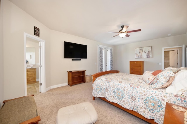 bedroom featuring light colored carpet, baseboards, a ceiling fan, and ensuite bath