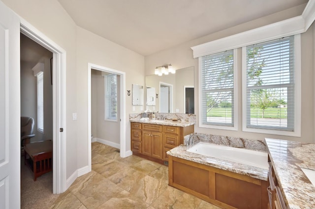 full bathroom with baseboards, a healthy amount of sunlight, a garden tub, and vanity