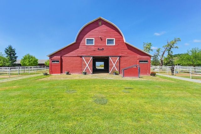 view of barn with a lawn and fence