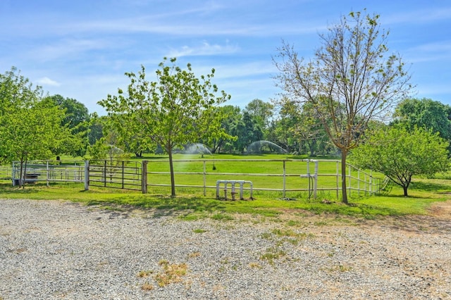 view of gate with a rural view, a lawn, and fence