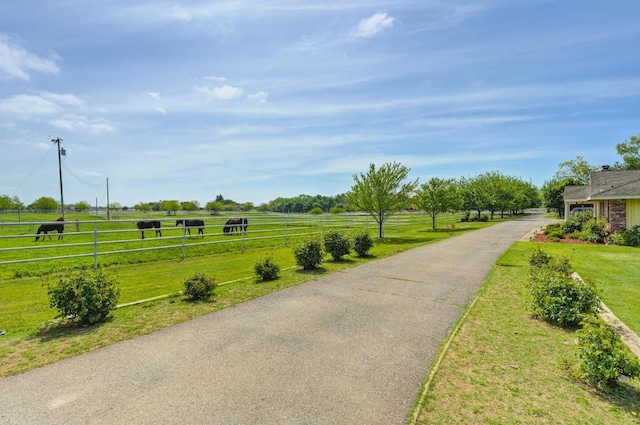 view of property's community with fence, a yard, and a rural view