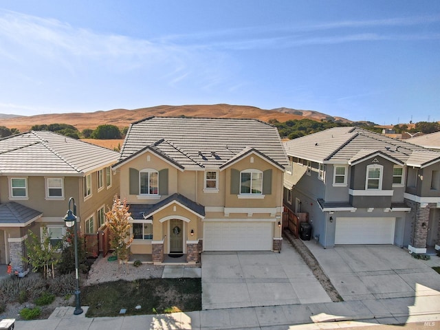 traditional-style house featuring a garage, concrete driveway, a tiled roof, and stucco siding