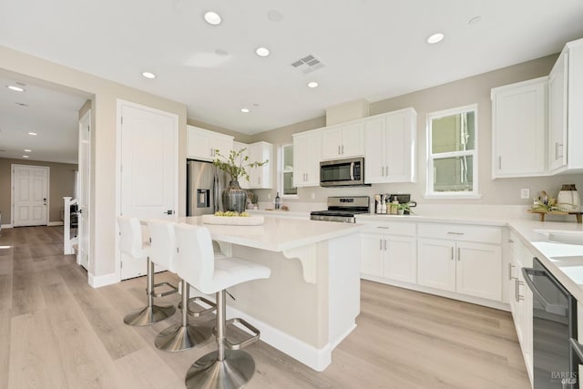 kitchen with a breakfast bar, visible vents, white cabinetry, and stainless steel appliances