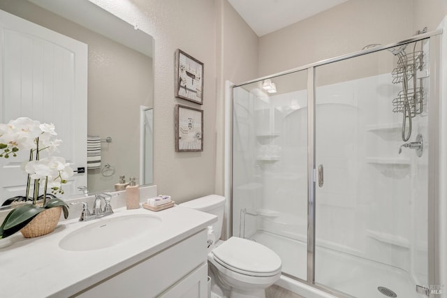 full bath with a shower stall, toilet, a textured wall, and vanity