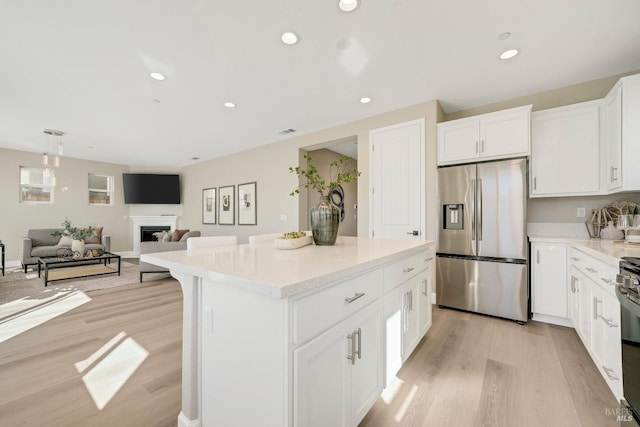 kitchen with light wood finished floors, stainless steel fridge with ice dispenser, a kitchen island, open floor plan, and white cabinetry