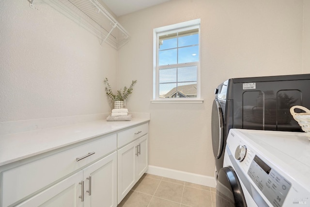 laundry area with cabinet space, light tile patterned floors, baseboards, and washer and clothes dryer