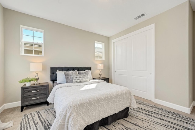 bedroom with light carpet, baseboards, visible vents, and a closet