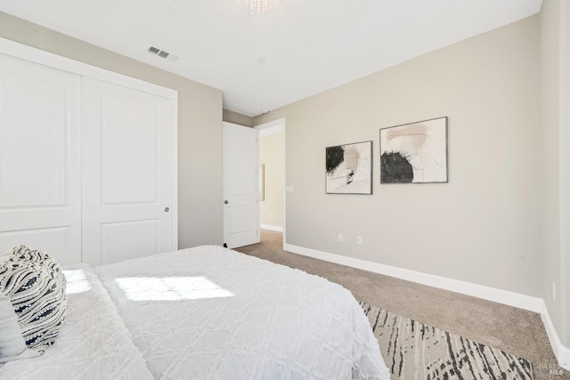bedroom with baseboards, a closet, visible vents, and carpet
