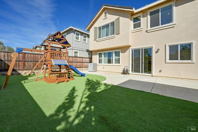 rear view of house featuring stucco siding, a yard, a fenced backyard, and a playground