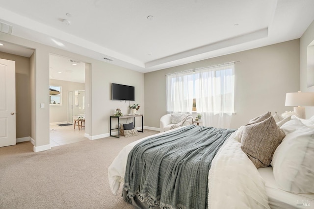 bedroom with visible vents, baseboards, a tray ceiling, and light colored carpet