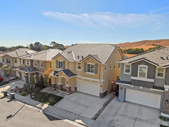 view of front facade with stucco siding, an attached garage, concrete driveway, and a tile roof