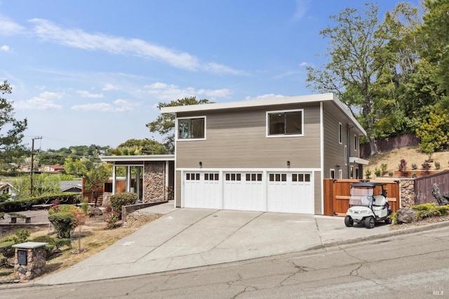 traditional home featuring fence, concrete driveway, stone siding, and a garage