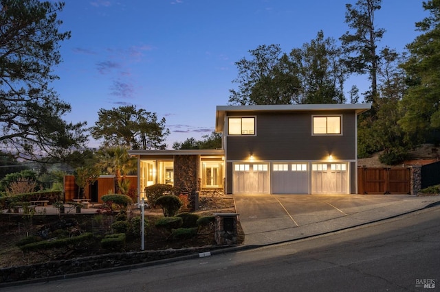 view of front of property with a garage, fence, concrete driveway, and stone siding