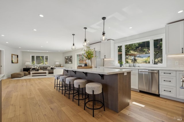 kitchen featuring a breakfast bar area, dishwasher, white cabinetry, and light wood-style floors