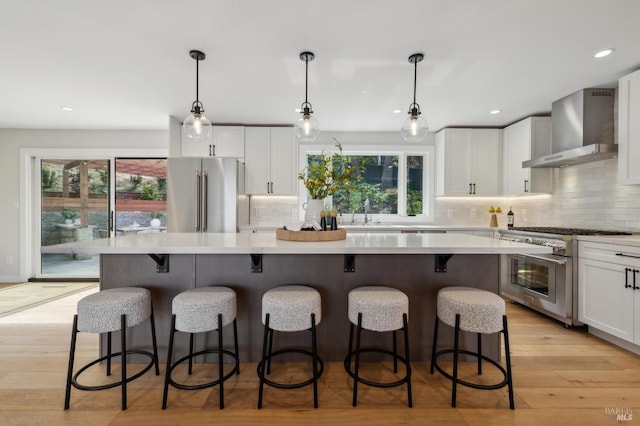kitchen with a center island, high end appliances, backsplash, and wall chimney exhaust hood