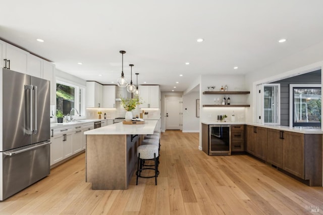 kitchen featuring open shelves, high end fridge, a breakfast bar, white cabinets, and beverage cooler