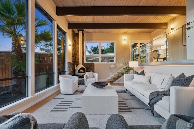 sunroom featuring a wood stove and beamed ceiling