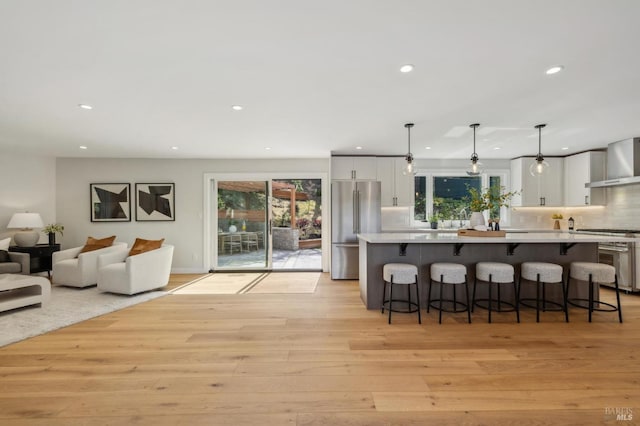 kitchen featuring high quality fridge, recessed lighting, and wall chimney exhaust hood