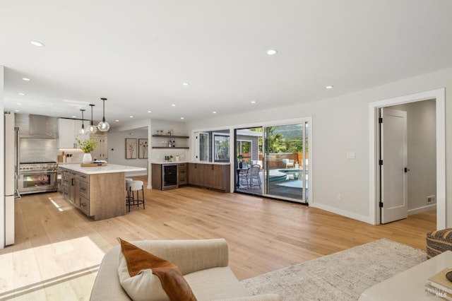 living room featuring beverage cooler, recessed lighting, light wood-style flooring, and baseboards