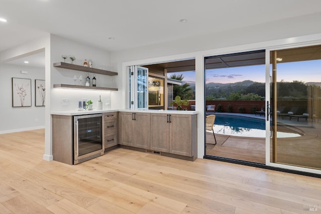 bar featuring wine cooler, recessed lighting, light wood-style flooring, and wet bar