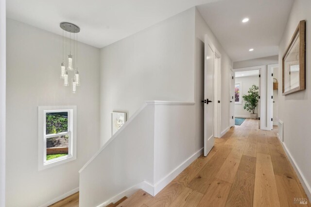 corridor featuring light wood-style flooring, an upstairs landing, visible vents, baseboards, and recessed lighting