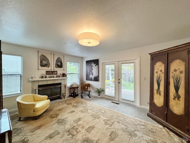 living area featuring visible vents, french doors, a tile fireplace, and a textured ceiling
