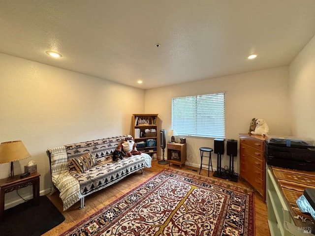 living area with baseboards, wood finished floors, and recessed lighting