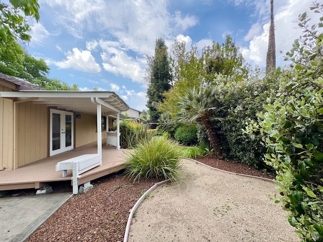 view of yard featuring a wooden deck and french doors