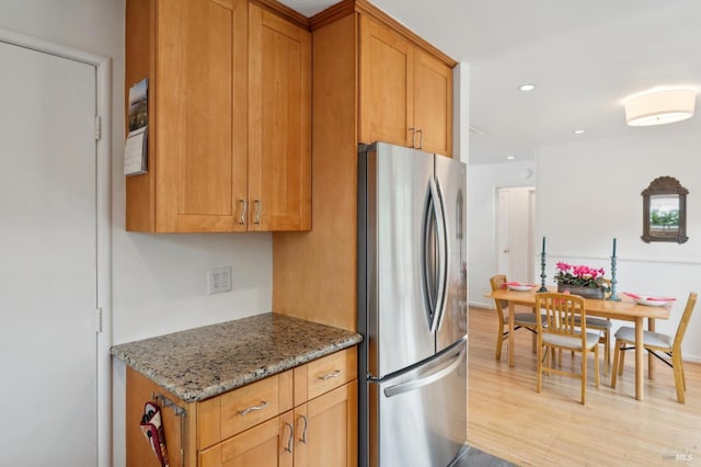 kitchen with light stone counters, brown cabinetry, freestanding refrigerator, light wood-style flooring, and recessed lighting