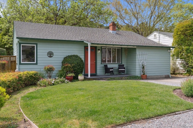 ranch-style house featuring a chimney, a front yard, a shingled roof, and covered porch