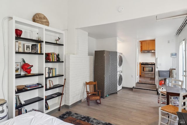 bedroom featuring baseboards, stacked washer / drying machine, and wood finished floors
