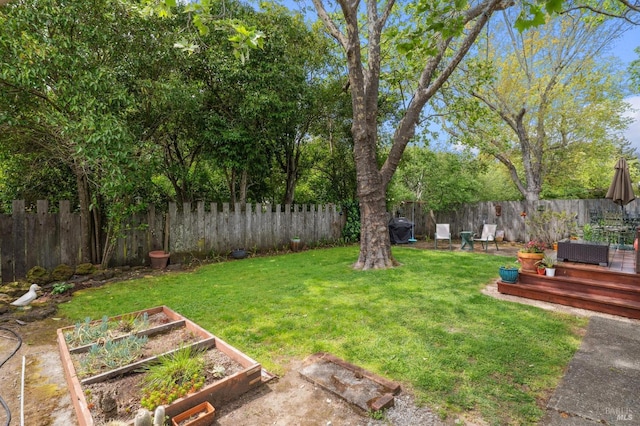 view of yard with a fenced backyard, a garden, and a deck