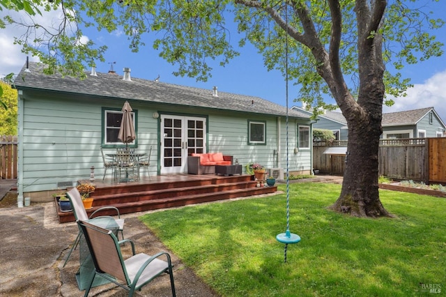 rear view of property featuring a wooden deck, french doors, a lawn, and a fenced backyard