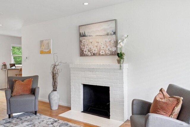 living area featuring recessed lighting, wood finished floors, a brick fireplace, and baseboards