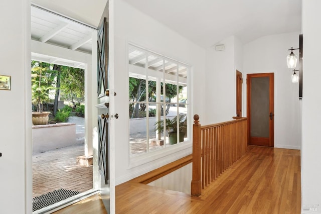 doorway to outside with wainscoting, lofted ceiling with beams, and wood finished floors