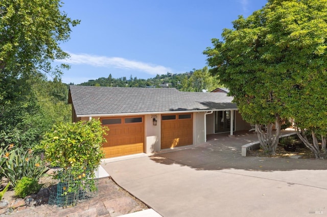 ranch-style house featuring a garage, stucco siding, roof with shingles, and concrete driveway