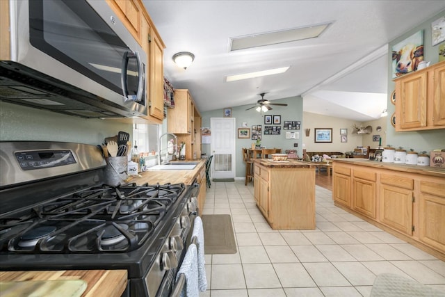 kitchen featuring stainless steel appliances, a sink, vaulted ceiling, butcher block countertops, and light tile patterned floors