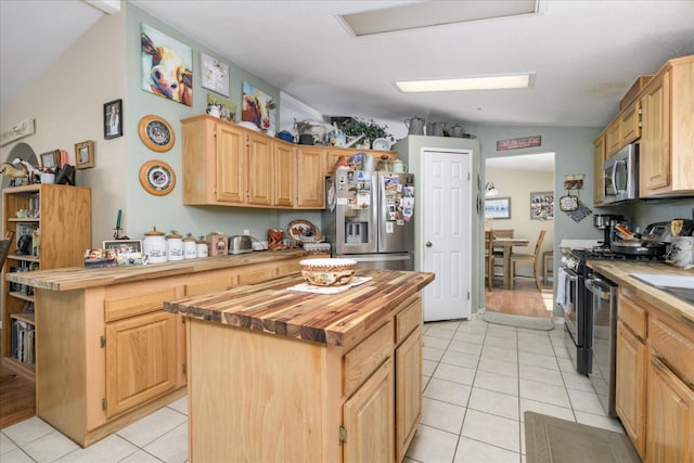 kitchen featuring light brown cabinets, butcher block countertops, light tile patterned flooring, stainless steel appliances, and a kitchen island