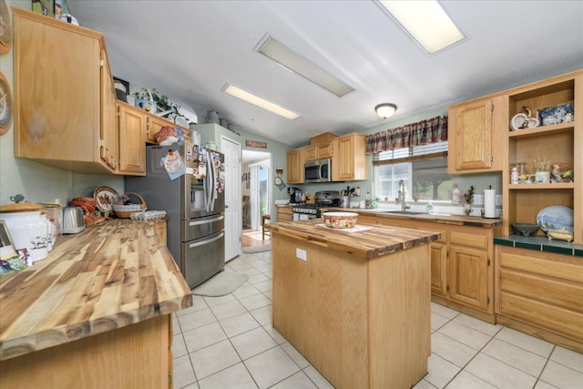 kitchen with stainless steel appliances, a center island, a sink, light tile patterned flooring, and butcher block countertops